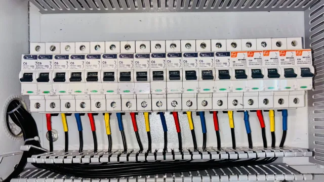 An open technical handbook and coiled cable on an electrician's workbench